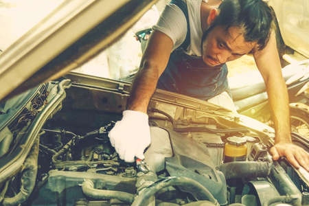 Concept of car maintenance in service stations : Portrait young car repair worker dedicated to the maintenance of the car, check the repair phase : Mechanic Check the tightness of the rubber hose.の写真素材