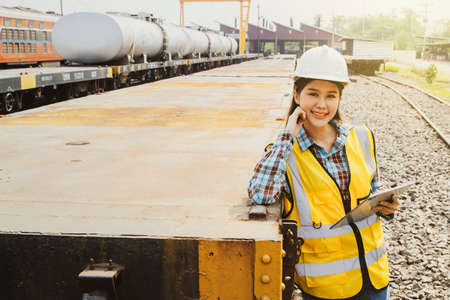 Professional senior portrait female engineer safety helmet holding laptop computer works at the diesel locomotive railway station garage standing smiling looking at the camera in aの写真素材