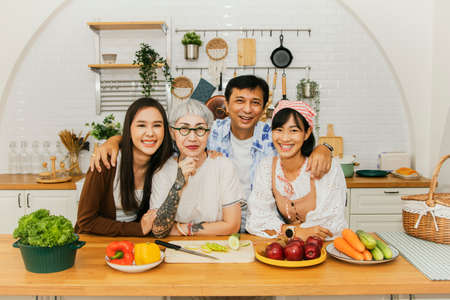 Perfect happy family : Portrait big asian family parents and sister Healthy posing for current photo in the kitchen at home while smiling happily as they look at the camera.の写真素材