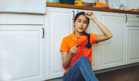 Female delivery service worker, tired of the delivery and hard work, left her job and returned home to rest exhausted : Tired stressed dismal asian woman sits exhausted and rests hの写真素材