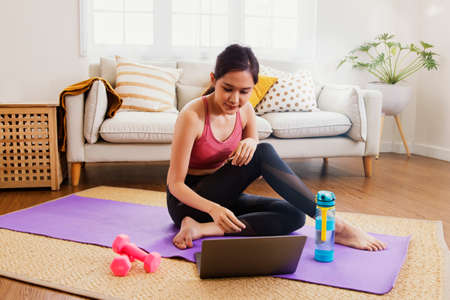 Young asian woman lifestyle exercises living room study at home with exciting interest in...
