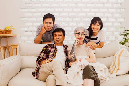 Portrait of four people in a warm family : Happy Asian families take pictures together to commemorate memories and gifts in a home with lovely parents, brother and sister.の写真素材