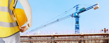 Rear view architect engineer female worker holding safety helmet supervising building construction and field heavy industrial cranes : Select focus : Select focusの写真素材