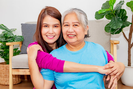 Headshot grateful daughter beautiful hugs the elderly mother lovingly in the living room takes care of the millennial mother's health stay healthy be happy together look at the camの写真素材