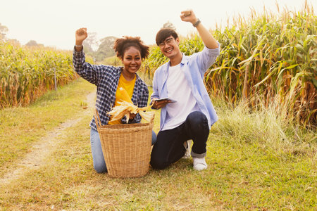 Asian farmer couple and an african american woman who love each other planting corn congratulate happy raising fists smile happy on the success of the farming of the corn farm nearの写真素材