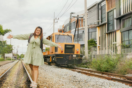 Fat asian woman happy carefree traveling taking pictures on the rails strolling as she reaches her destination in the city.の写真素材