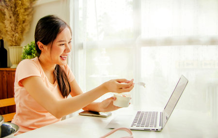 Asian women sit and make fresh milk ice cream and chat online via laptop camera and show off eating delicious ice cream : Selection focus thの写真素材
