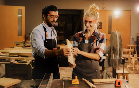 Woodworking lovers in the furniture manufacturing industry work together on a saw blade machine table wearing safety glasses. Work, choose lumber with care and creativity.の写真素材