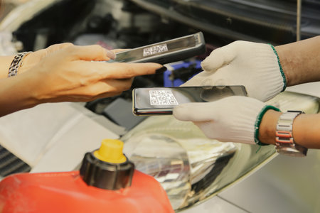 Auto mechanic using a mobile phone to check the condition of the car