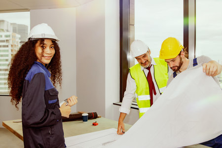 Talented female architect in construction engineering smiles at an office building renovation plan meeting with senior architects and blueprint consultants.の写真素材