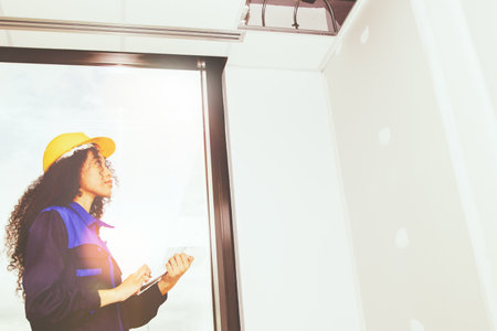 Female worker wearing helmet inspects the office ceiling structure in the building under construction and interior renovation to implement the safety system with great interest andの写真素材