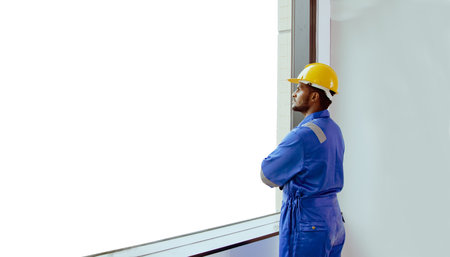 Asian male worker working construction site in a tall building looking out of the glass window of the mmpty mock up area and reflects on his positive and inspirational.の写真素材