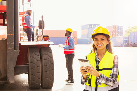 Portrait of a smiling female worker using digital tablet while standing in container yard