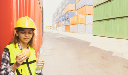 Portrait caucasian young woman cute in uniform and helmet standing relaxed for break with hamburger...