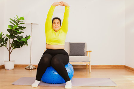 Healthy obese asian women want to lose weight with too much fat : Arm stretching sitting exercising on gymball playing sports activities at home yoga lifestyle for health and relaxの写真素材