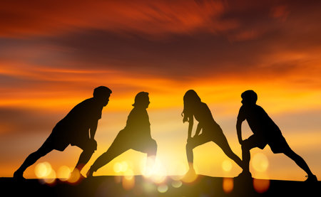 Silhouette of a group of people doing sports outdoors at sunsetの写真素材