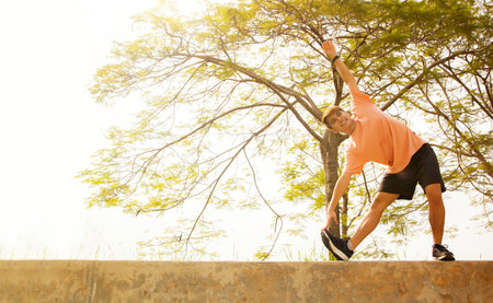 Young man doing stretching exercise in the park. Healthy lifestyle concept.の写真素材