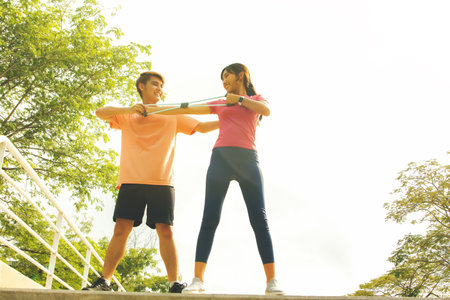 young woman and man exercising with resistance band in the parkの写真素材