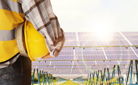 engineer holding yellow helmet and solar panel in photovoltaic power plantの写真素材