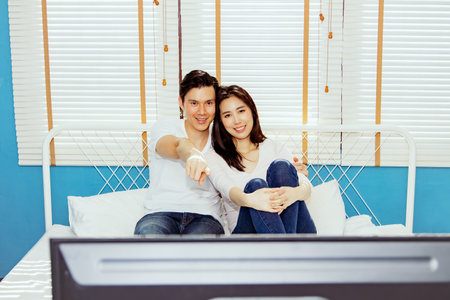 Happy asian couples spend their holidays watching entertainment programs at home in the comfort of...