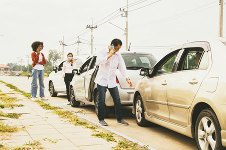 Man who was involved in a three vehicle collision standing stressed looking at the damage use phone to call the insurance company to clear and assess the initial damage to the otheの写真素材