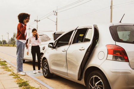 Young asian woman and african american woman driving recklessly in a road accident rear end car damage using smartphone to call car insurance company to take action and negotiate rの写真素材