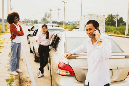 Man who was involved in a three vehicle collision standing stressed looking at the damage use phone to call the insurance company to clear and assess the initial damage to the otheの写真素材