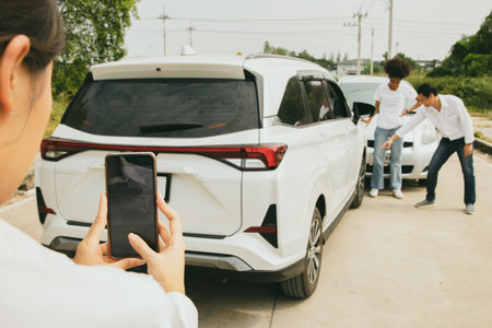 Female officer of an automobile insurance company uses smartphone to take a photo of the license plate number as evidence of the accident to help coordinate compensation for the inの写真素材