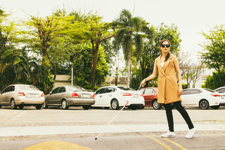 Beautiful blind asian woman crosses the road using cane to guide the walk slowly for safety while carefully walking to the opposite side to prevent accidents : Accident insurance fの写真素材