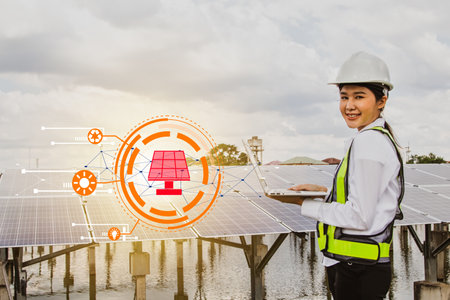 Professional asian female electrical engineer in hard hat works in the field checking solar panel installation site on suburban well typing results on tablet online system to conneの写真素材