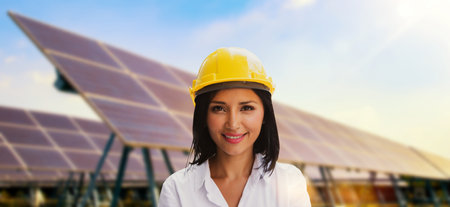 Beautiful cauasian female in yellow helmet working solar panel renewable energy clean energy green energy photovoltaic large scale solar panel power station provides supply power tの写真素材