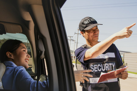 Male security guard provides travel information young woman driving private car came to ask for travel information and pointed to the right direction to reach her destination and mの写真素材