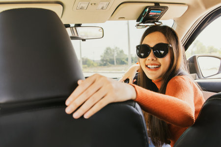 Concept teach driving : Happy beautiful young asian newbie girl in sunglasses preparing for driving lesson taught by expert instructors from driving school drive safely on roadの写真素材