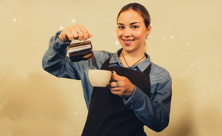 Coffee and food service business concept : Portrait hispanic lady barista in apron smiling professional smiling preparing and pouring milk from jug into hot cup with professional jの写真素材