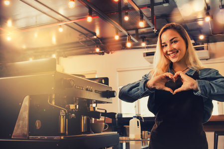 Portrait beautiful female hispanic barista who serves the work in front of the counter sends hearts to you and lovely customers who come to use the service with sinceerity.の写真素材