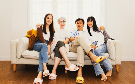 Perfect happy family : Portrait asian family Parents and sisters were together sitting on the sofa looking at the present camera as a souvenir spending time together warmly in theの写真素材
