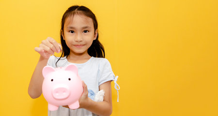 Portrait young girls asian elementary school students enjoy happy saving money use coins to put pink pig piggy bank Collect coins with pride : Saving allowance money for educationの写真素材