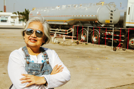 Portrait asian healthy senior female worker working as a fuel truck driver in a depot or gas station : Elderly female worker with experience and ability to transport NGV and oil inの写真素材