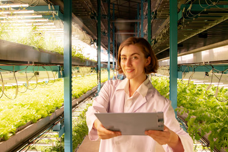 Female researcher holds research paper presenting hydroponic vegetable farm growing in a closed indoor cleanroom using Led Grow solar cells an innovative post growing technology wiの写真素材