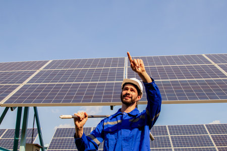 Male technician in charge of solar panels holding dirty solar panel cleaning tools preparing for cleaning work pointing finger instructing repair team to clean up dirty spots all oの写真素材