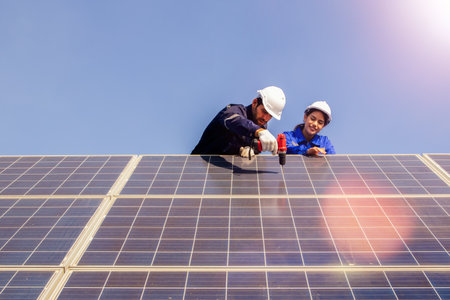 Male and female electrician technicianin worker maintenance forklift inspects shaky solar panel, demonstrating using power drill to secure structure with drill for safetyの写真素材