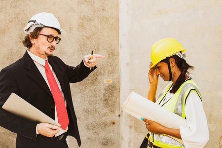 Architect male worker construction site supervisor standing and speaking ordering work asian female foreman works strictly according assigned order and pays attention to work safetの写真素材