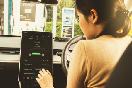 Back view young woman asian driving an EV electric car sit in the passenger compartment examining...