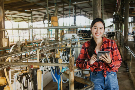 Portrait asian female health worker holding tablet inspecting dairy farm, factory rural cow farm, inspecting the cleanliness of milking machine that is hygienic and safe accordingの写真素材