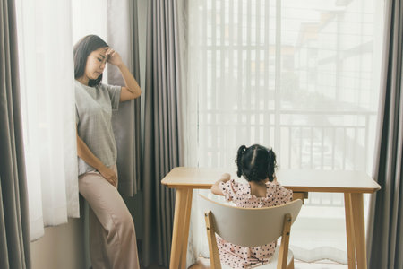 Asian mother and daughter sitting at the table in the living room.の写真素材