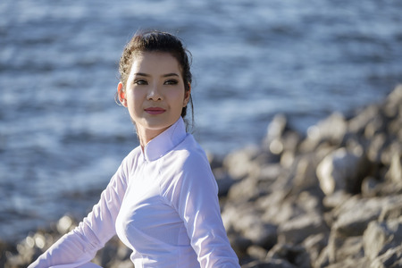 Beautiful woman in Vietnam culture traditional relaxing on lake beside blue waterの写真素材