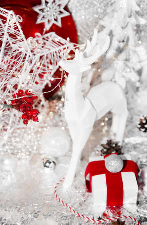 Christmas red, xmas white reindeer, red plate, gift, red ribbon, mountain ash, rowan, christmas tree and balls, on white background, with sweets, cinnamon, winter cone and lightsの写真素材
