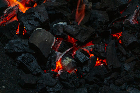 Coals with sparks in a huge old metal grill background