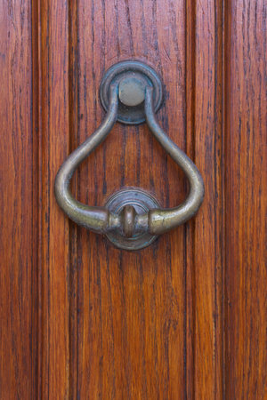 Antique metal door knocker on a wooden door close upの写真素材