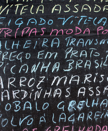 Detail of a portuguese menu written in multicolored chalk on a black chalkboard. handwritten menu backgroundの写真素材
